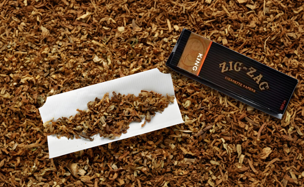 King size Zig-Zag rolling papers Houston smoke shops carry, shown with loose tobacco on an open white paper leaf.