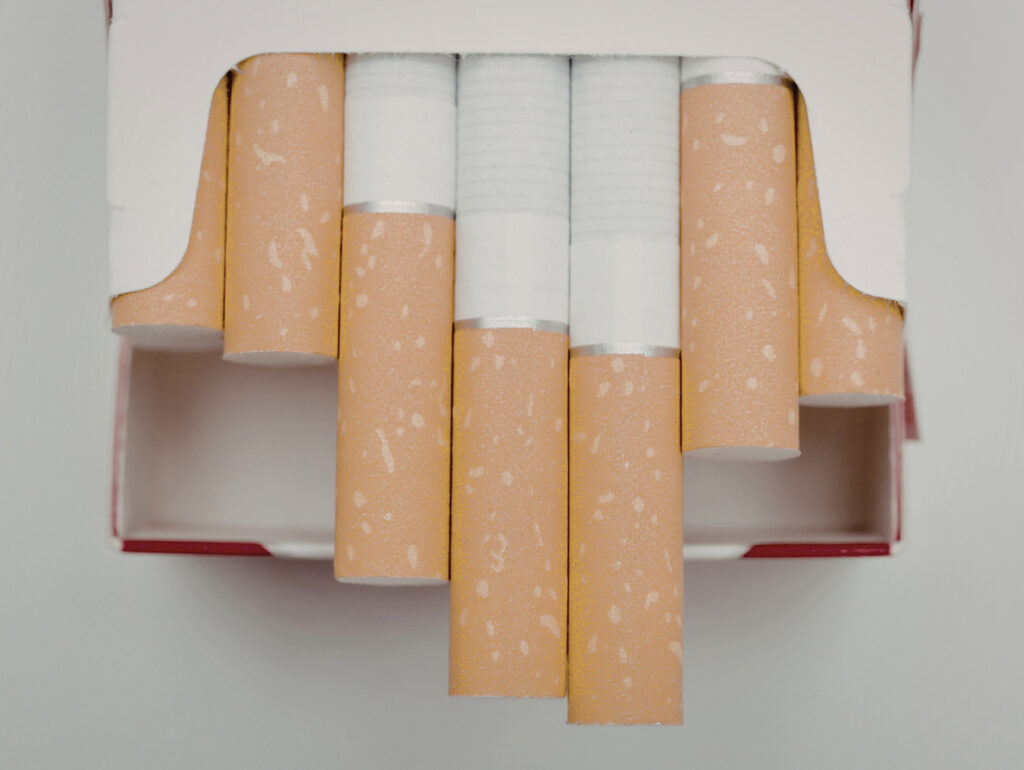 Inside an open pack at a cigarette shop Tulsa, showing a closeup of cigarettes with orange filters and white paper.