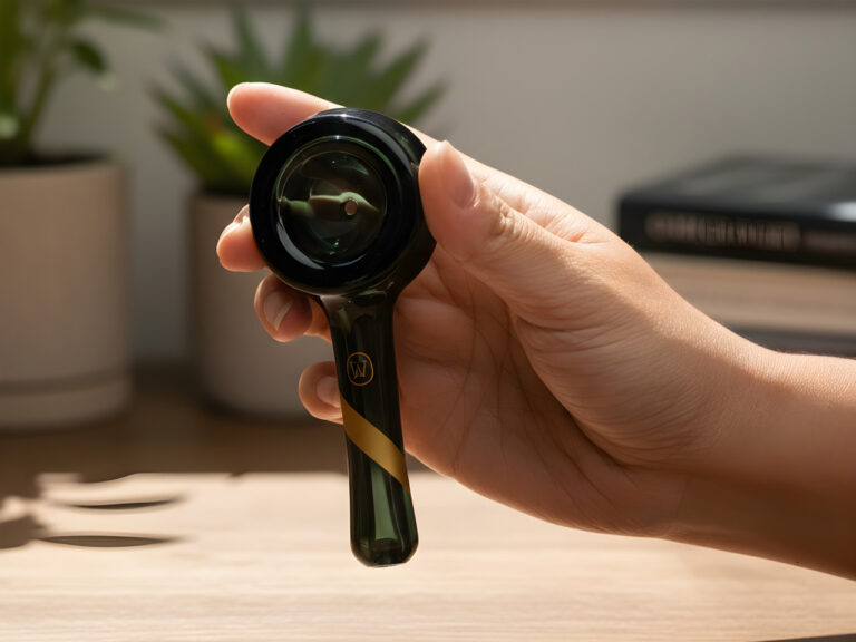 Close up of a hand holding sleek dark green glass pipes Tulsa smoke shops offer for portable and stylish sessions.