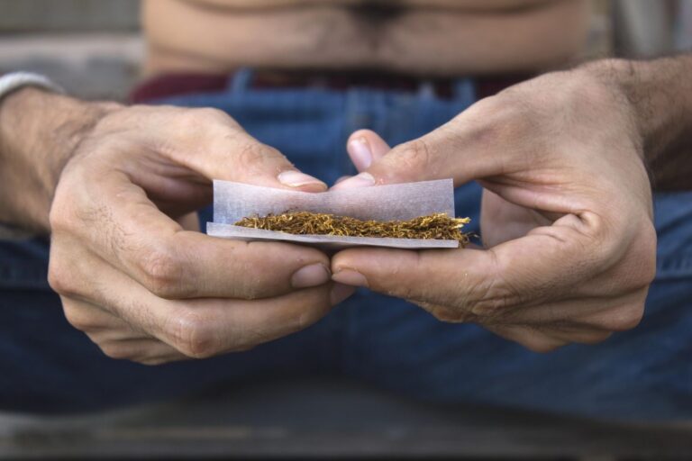 Close up of hands preparing hand rolled cigarettes with quality paper and leaf from a local tobacco shop Houston TX.
