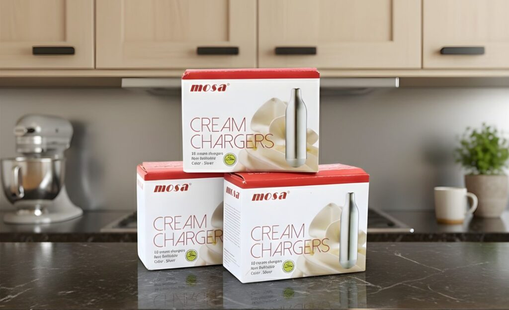 Three boxes of Mosa cream chargers n20 Owasso on a dark marble kitchen counter with a stand mixer in the background.