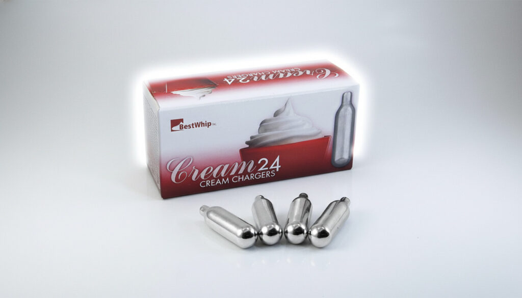 Product shot of a box of N2O whipped cream Sapulpa chargers and four loose metal cartridges on a clean white background.