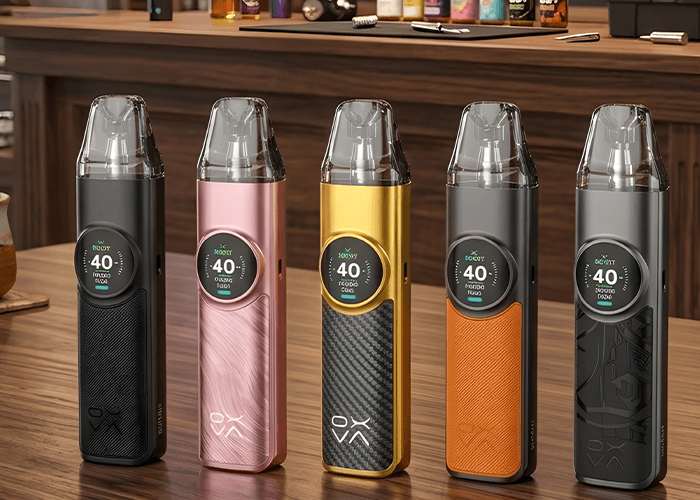 Selection of OXVA vape pod kits in various colors on a wooden counter at a premium smoke shop Houston location.