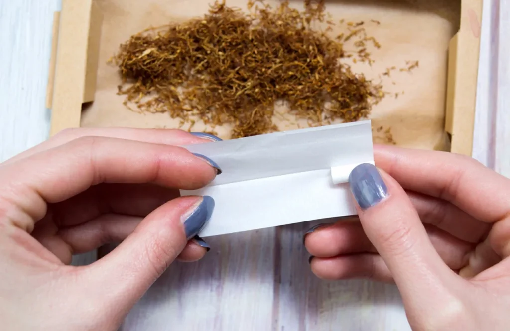 A close-up view of hands rolling loose tobacco into quality Rolling papers tulsa, perfect for RYO enthusiasts.