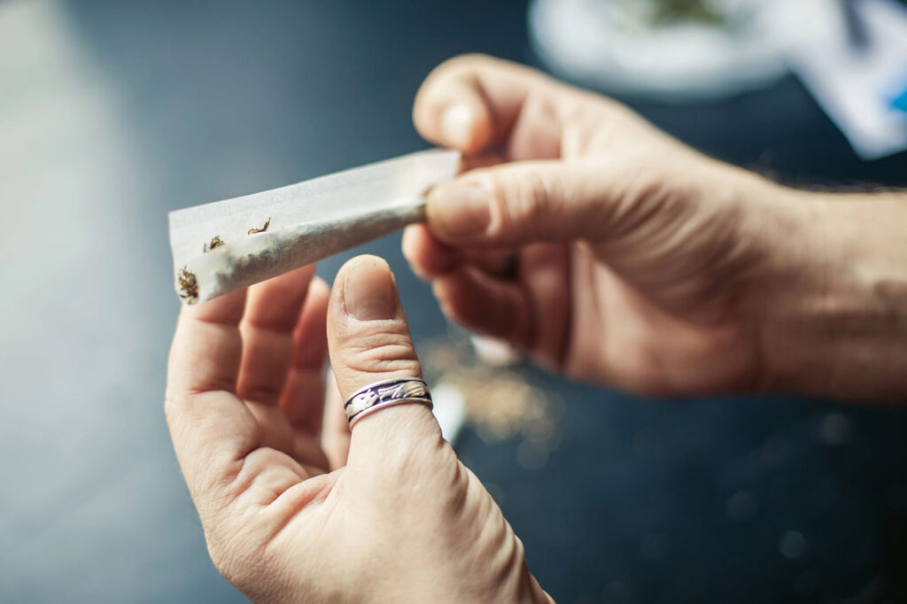 Close up of hands rolling cannabis into a cone shape using organic rolling papers Tulsa smokers prefer for quality.