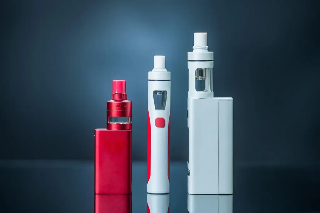 Three distinct types of e-cigarettes: a red mod, a white pen, and a silver box mod. Find quality e-cigarettes broken arrow at our shop.