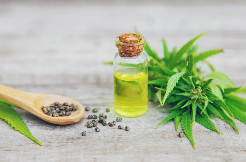 Hemp extract bottle with seeds on a wooden spoon, showcasing natural products from a cbd store broken arrow shop.