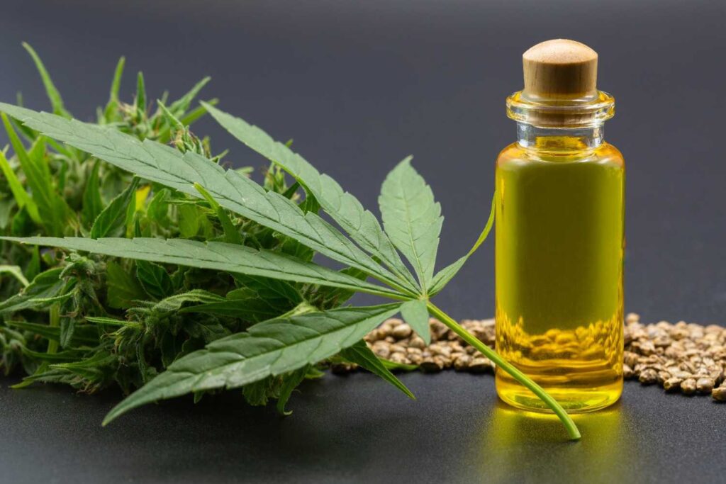 Premium cannabis oil bottle from a CBD store Broken Arrow with a fresh hemp leaf and seeds on a dark background.