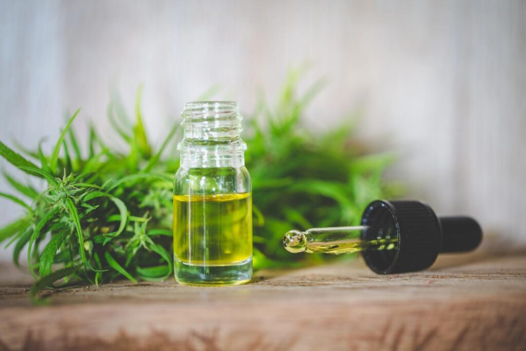 Pure cannabis extract bottle and open dropper on wood, featuring premium hemp greens from a trusted CBD store Sapulpa. 