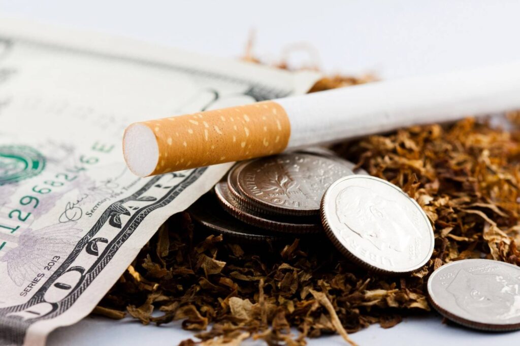 Loose leaf tobacco with a dollar bill and coins, highlighting the value at a premier cigarette shop broken arrow OK.