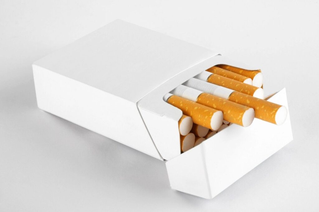 A blank white pack from a cigarette shop Tulsa lying flat with cigarettes partially sliding out of the box. 