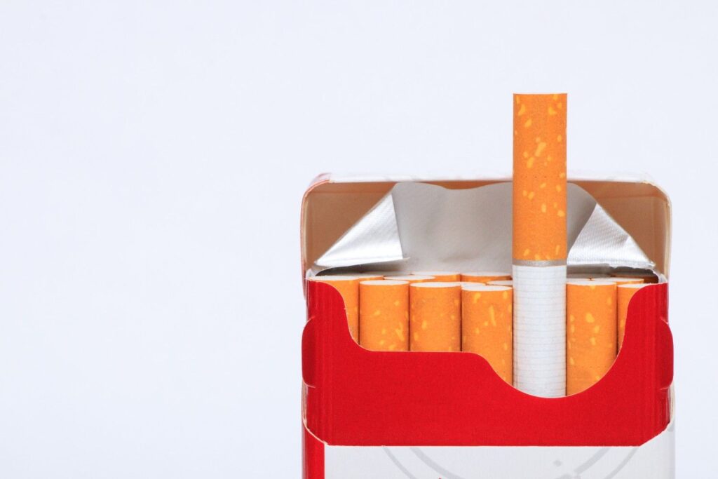 An open red pack from a cigarette shop Tulsa with one cigarette turned upside down showing the brown filter. 
