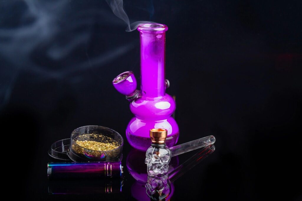 Purple glass pipes Tulsa bong kit with a matching lighter clear glass skull piece and herbal grinder on a dark backdrop