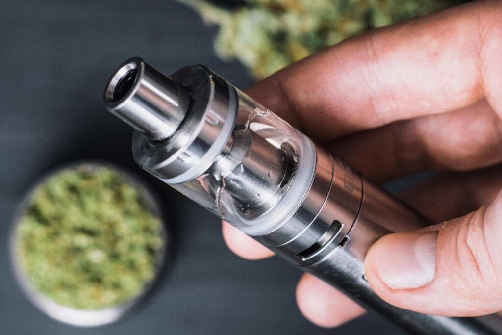 Hand holding a metallic vape pen with ground cannabis, perfect for exploring premium herbal vaporizers tulsa.