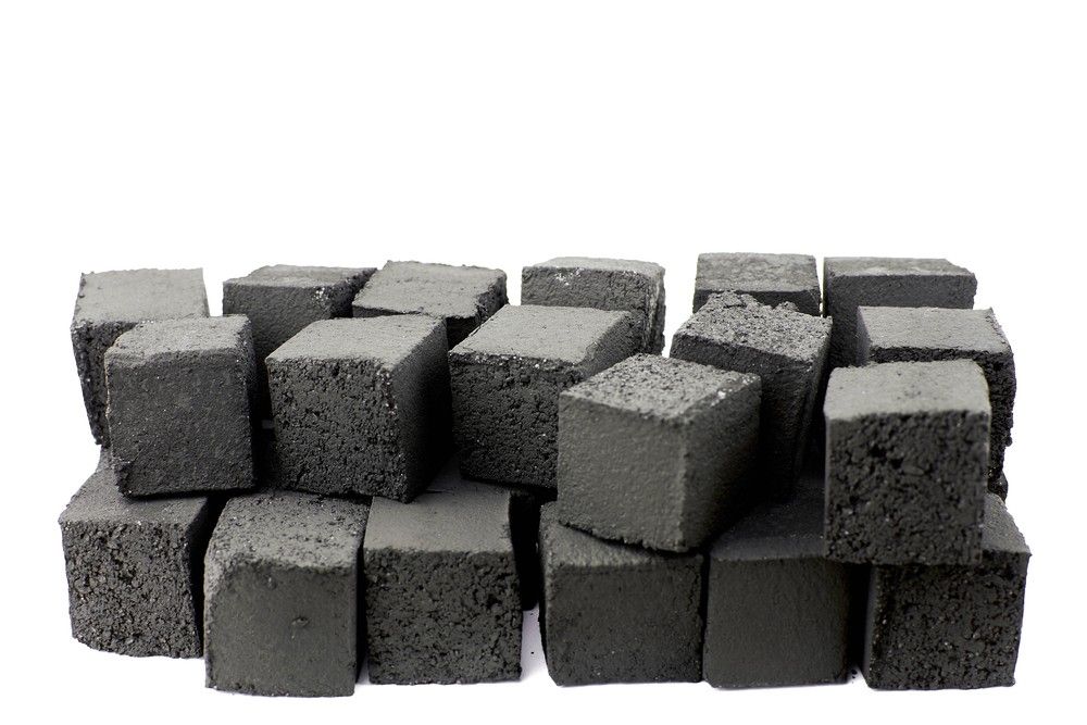 A large stack of premium, unlit coconut hookah charcoal cubes for sale, isolated on white, at our hookah shop houston.