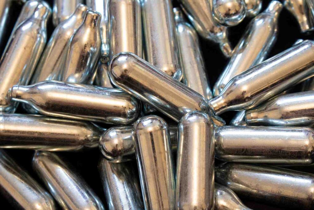 A dense pile of reflective metal nitrous oxide cream chargers, showing product stock variations for n20 Sapulpa. 