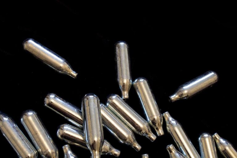 Scattered whippit chargers and shiny silver nitrous oxide canisters, captured in an n20 Sapulpa studio setup.