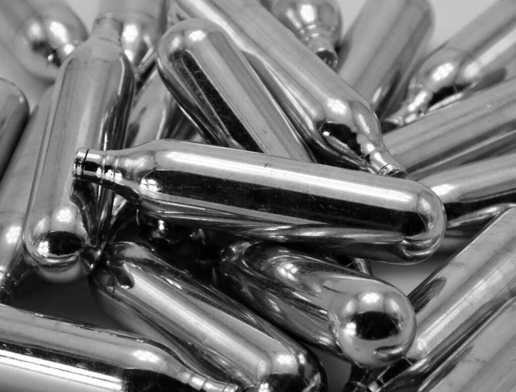 Close up of metallic nitrous oxide chargers Tulsa, providing essential wholesale catering supplies for businesses.