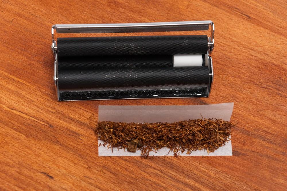 Overhead shot of rolling machine with filter and tobacco prepared on a paper sheet. Where to buy rolling papers sapulpa.