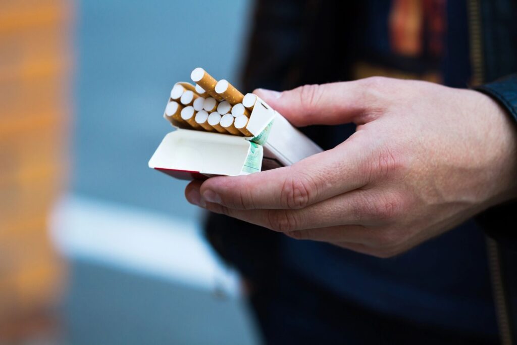 Close up of a person holding an open pack of cigarettes outside a popular cigarette shop broken arrow destination.