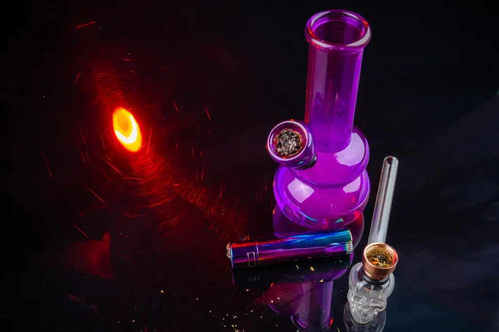 Premium smoke accessories Tulsa featuring a purple glass water pipe, skull-shaped hand pipe, and iridescent lighter.