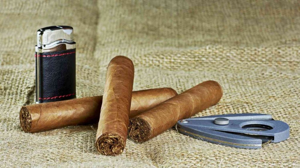 Premium cigars with a cutter and lighter on burlap at a smoke shop Sapulpa location for aficionados.
