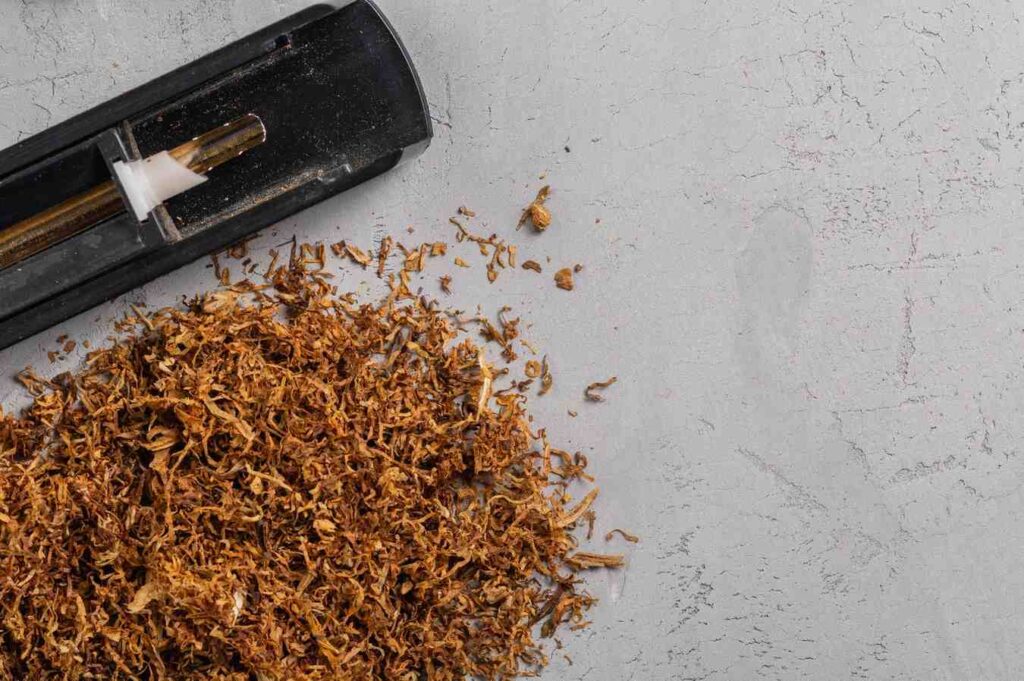 Loose leaf blend next to a classic cigarette injector machine on a concrete desk from a tobacco shop Houston.
