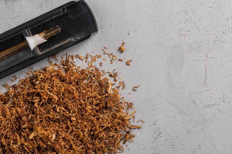 Loose leaf blend next to a classic cigarette injector machine on a concrete desk from a tobacco shop Houston.