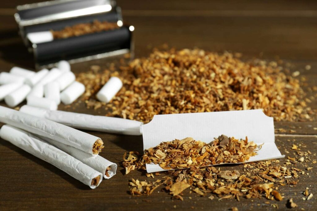Hand rolling tobacco with white filter tips and a rolling machine from a local tobacco store Tulsa shop supply.