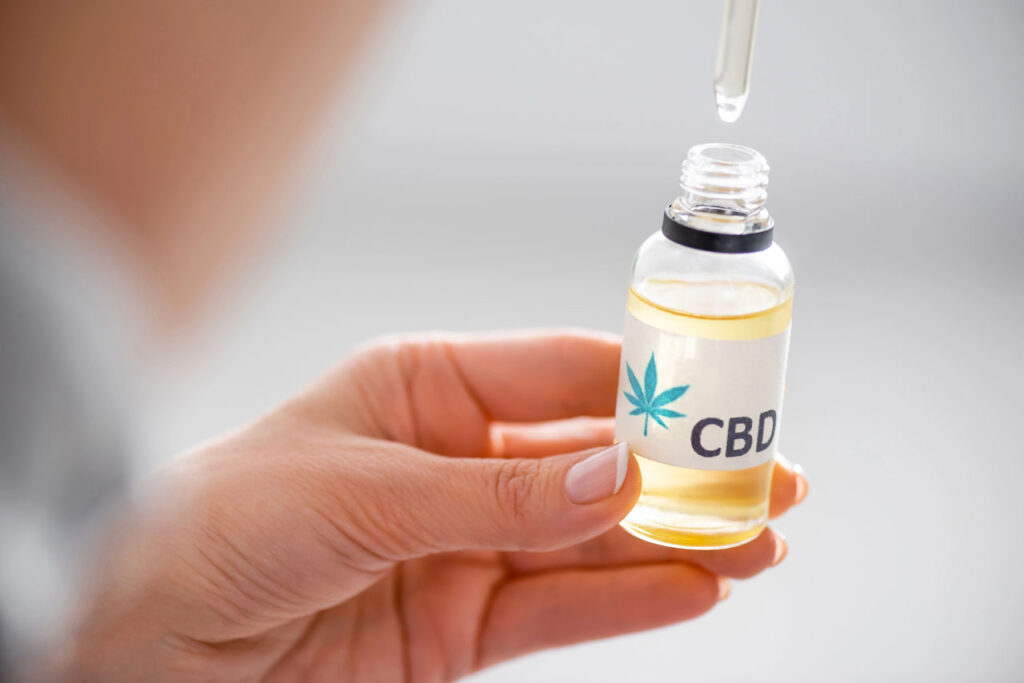 A customer holding a clear liquid extract bottle purchased from a wellness-focused CBD shop Tulsa.