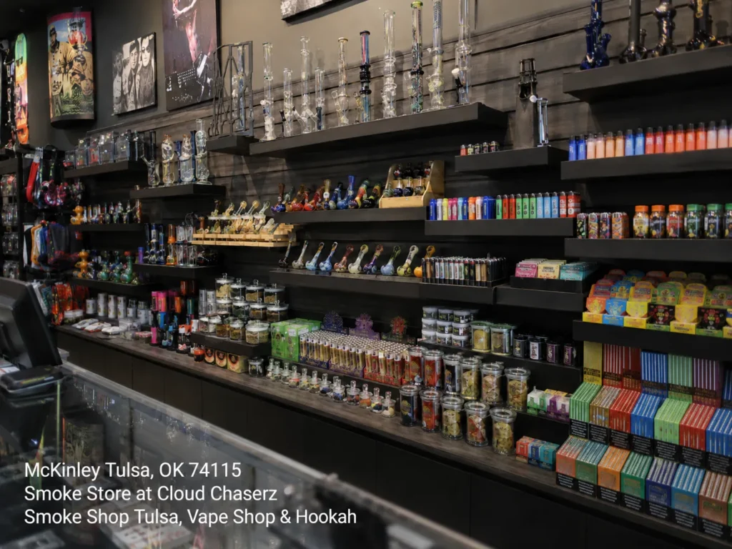 Wall shelves stocked with glass bongs, colorful pipes, and lighters inside the Cloud Chaserz smoke store tulsa.
