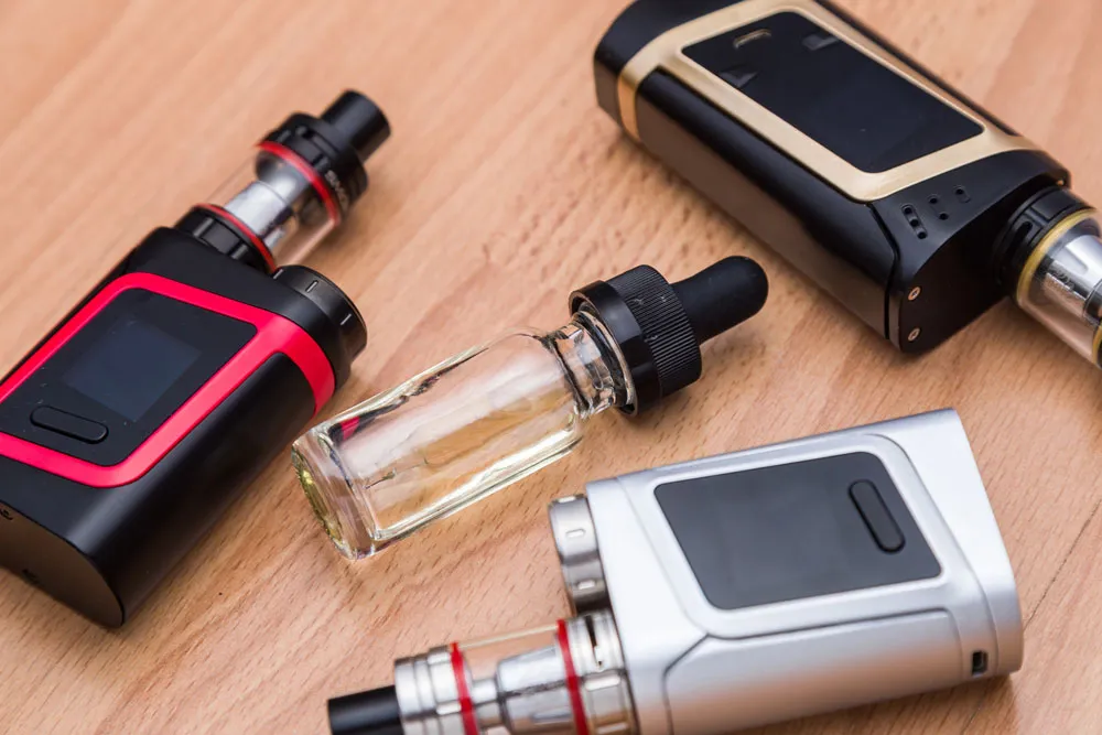 Premium vape supplies Sapulpa selection featuring advanced box mods, sub-ohm tanks, and a clear e-liquid dropper bottle.