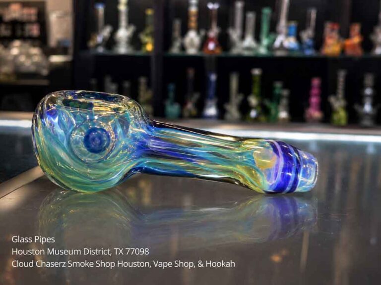 Artistic blue and green glass pipes at a Houston Museum District shop, reflecting on glass.