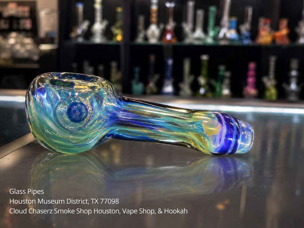 Artistic blue and green glass pipes at a Houston Museum District shop, reflecting on glass.