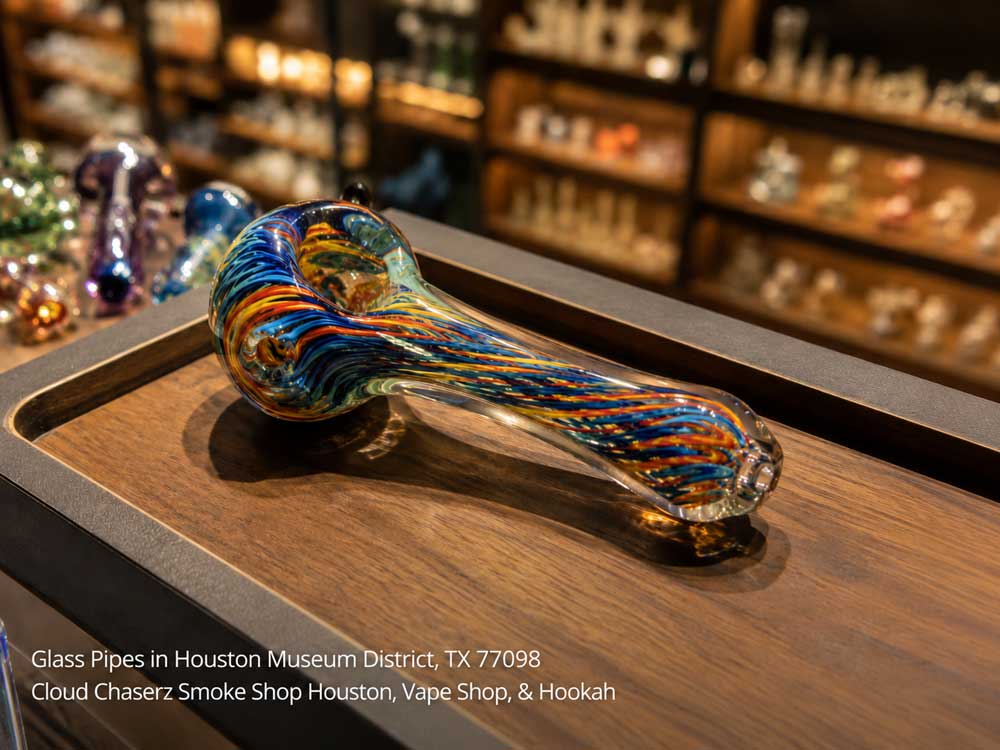 Vibrant swirling blue and orange glass pipes in a Houston smoke shop display case.