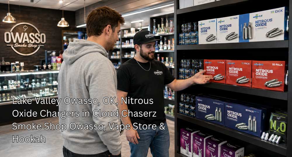 A smoke shop employee showing 10-pack nitrous oxide chargers owasso boxes to a customer at the store shelf.